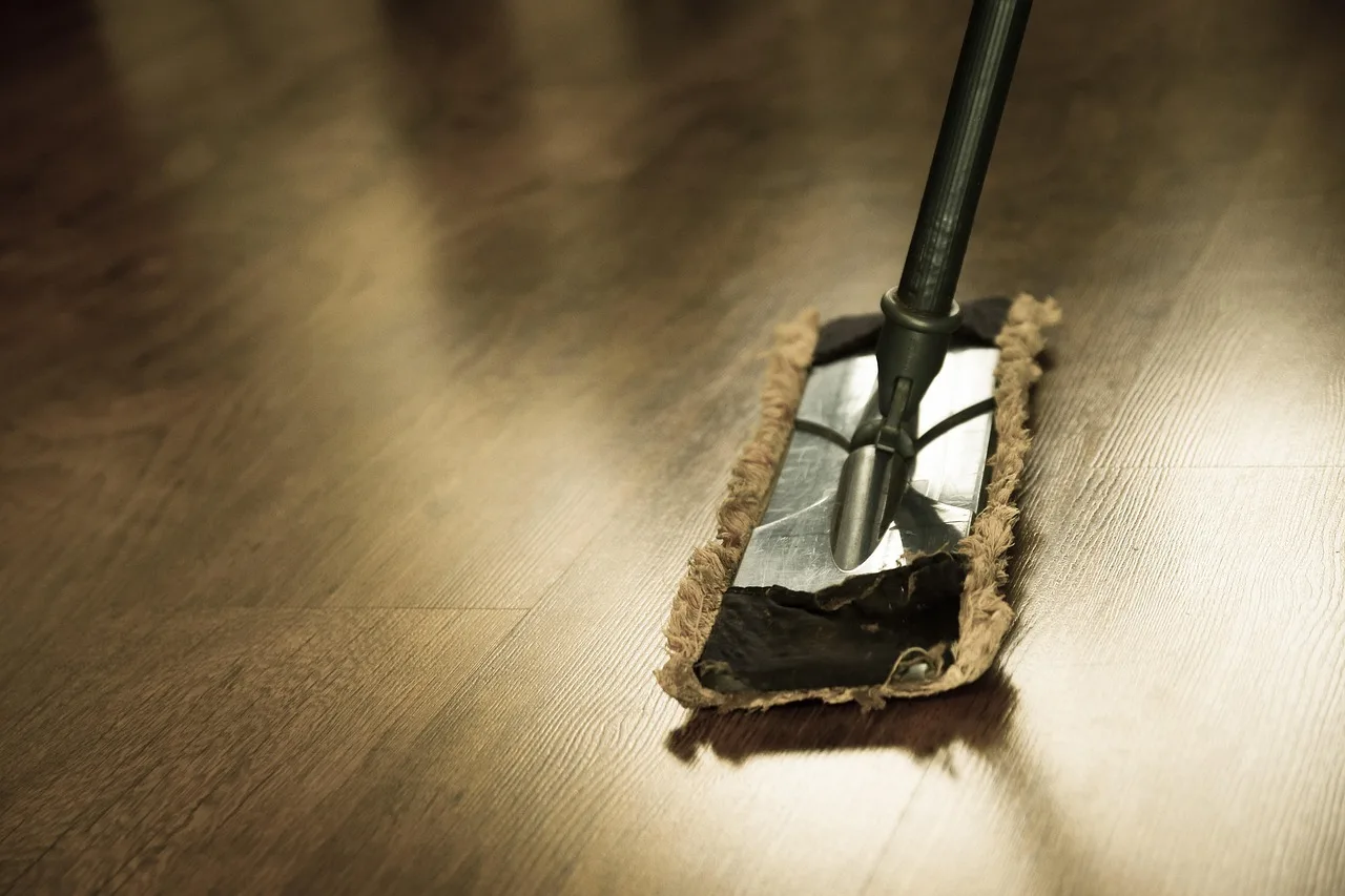 Donna che pulisce un pavimento con ammoniaca, mostrando tecniche di pulizia efficaci.